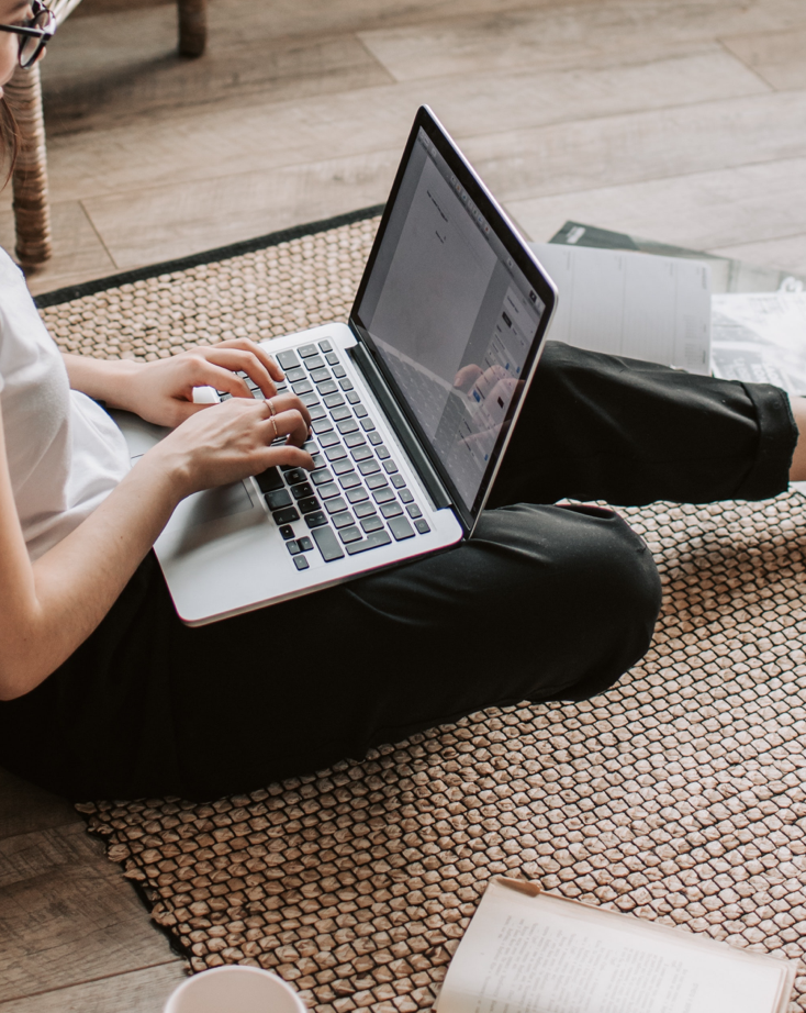 Undistinguishable woman sitting on the floor working on a Macbook Pro